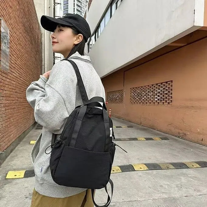 Simple solid colour nylon backpack shown in blue, with curved shoulder straps and a front lock.