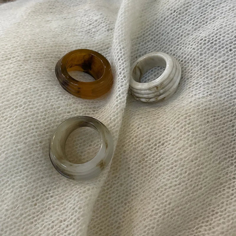 Geometric irregular resin wide ring in brown and white colour options on a hand.