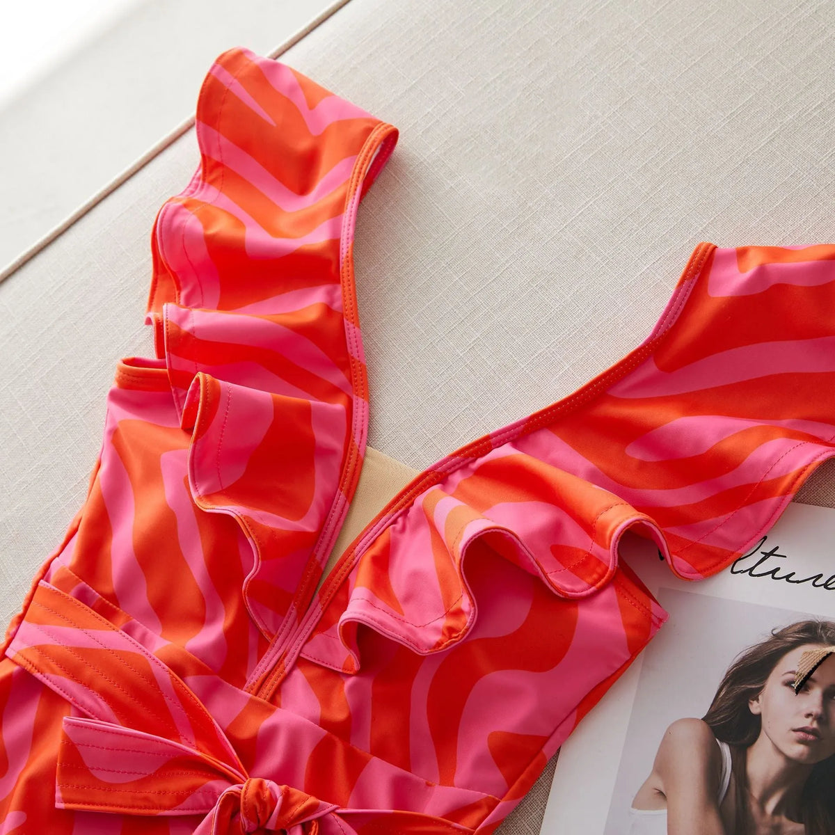 Women's deep V-neck one-piece swimsuit with mesh stitching and ruffled shoulders in a printing pattern.