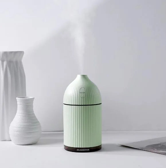 White ultrasonic aromatherapy diffuser with LED light, 300ml capacity, and USB cable on a wooden table