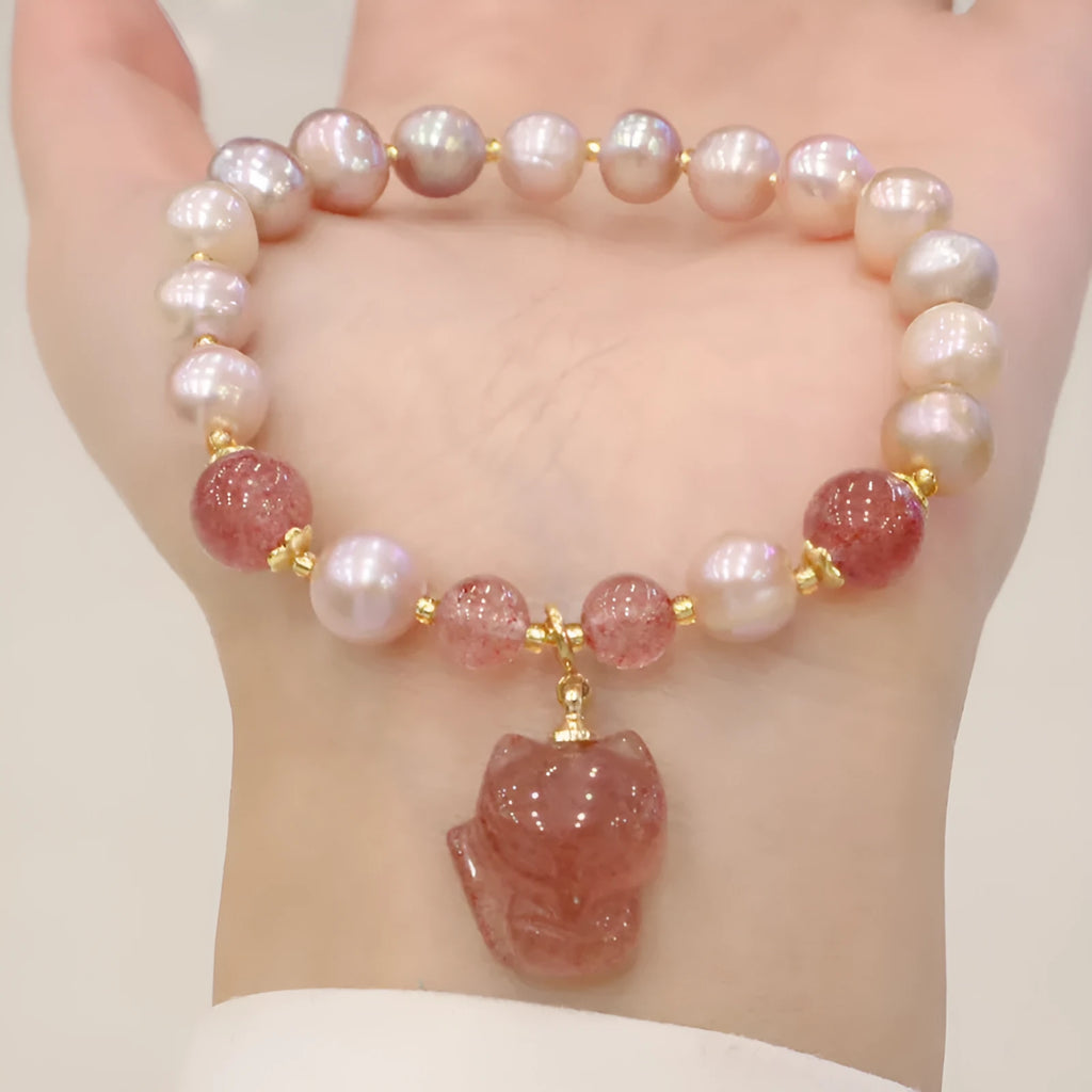 Light pink freshwater pearl bracelet with a strawberry quartz fox charm on a metal chain.