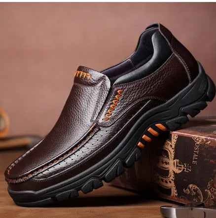 Black and brown leather business casual slip-on shoes with rubber outsoles on wooden floor