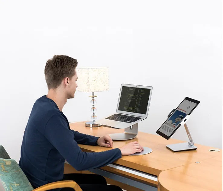 Silver foldable desktop holder supporting tablet with 360° rotation mechanism visible