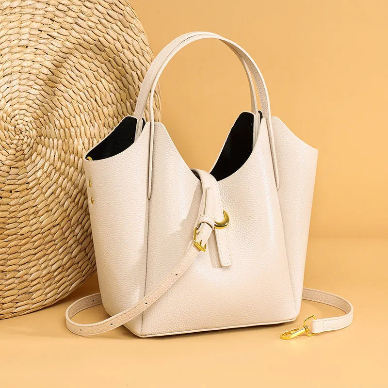 Genuine leather women's retro bucket handbag in beige with sewn detailing and an outer pocket.