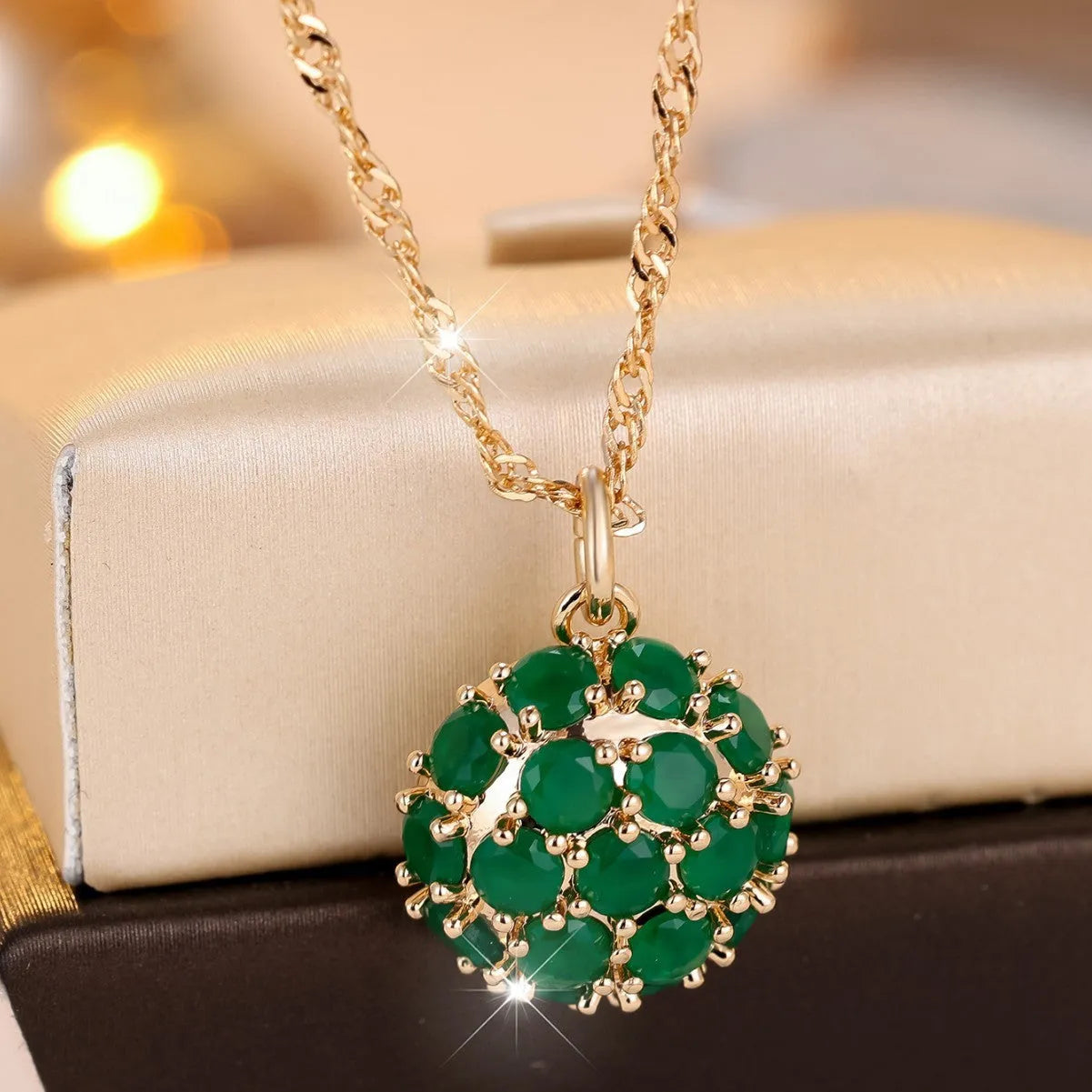 Champagne gold necklace with round emerald pendant and full diamond setting on an adjustable chain.