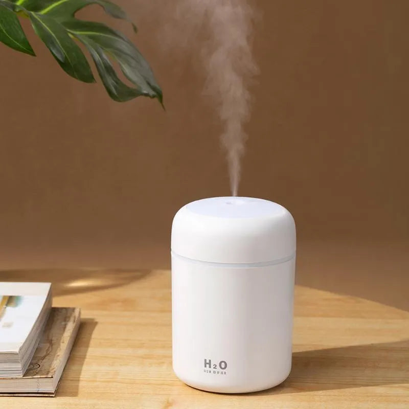 Pink USB mini humidifier with colourful lights on wooden desk