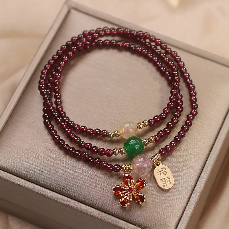 Women's crystal bracelet with pomegranate red cherry blossom beads and sequin details on a simple band.