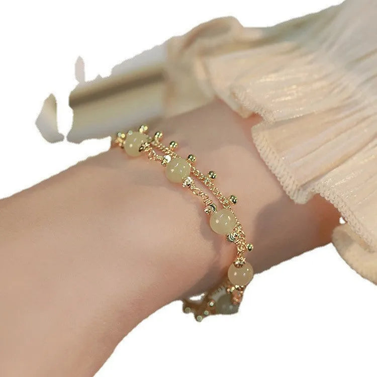 Natural Hetian Jade beaded bracelet with princess running motif on a wrist.