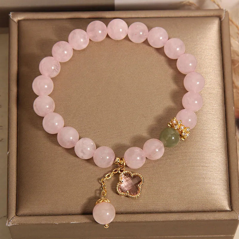 Pink crystal bracelet with four-leaf clover pendant and rhinestone details