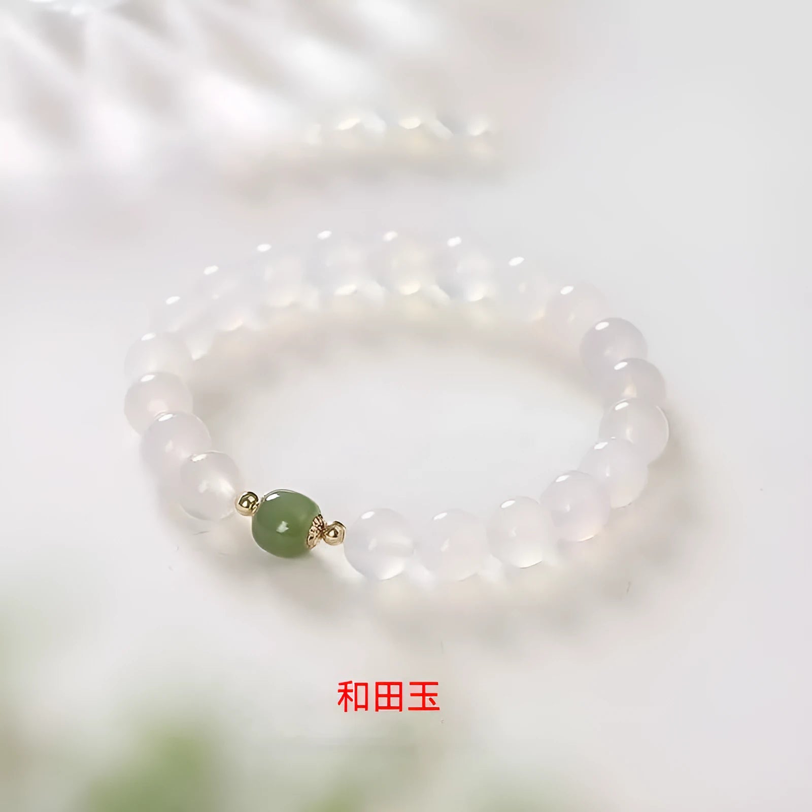Handmade natural white agate and Hetian jade crystal bracelet with cinnabar inlay on a wrist.