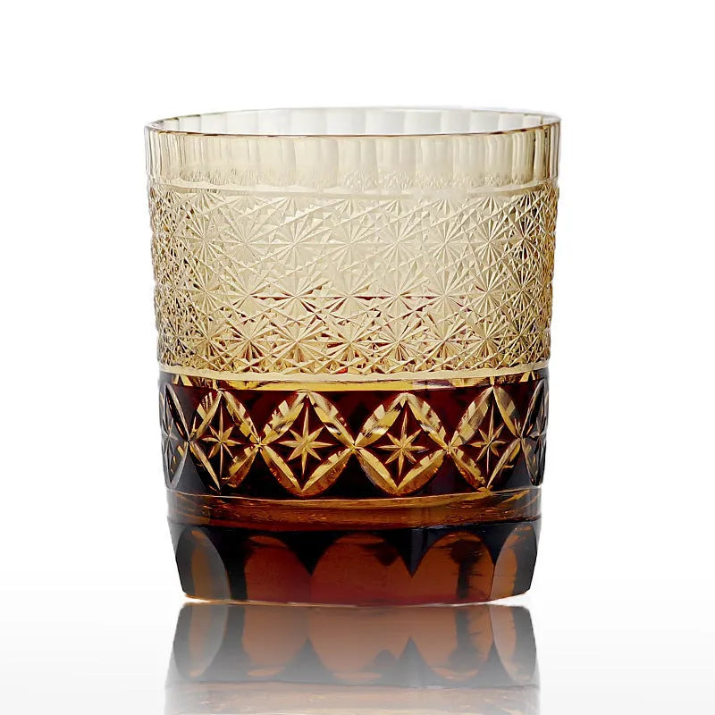 Hand carved Japanese style crystal whiskey glass in amber colour on a dark surface