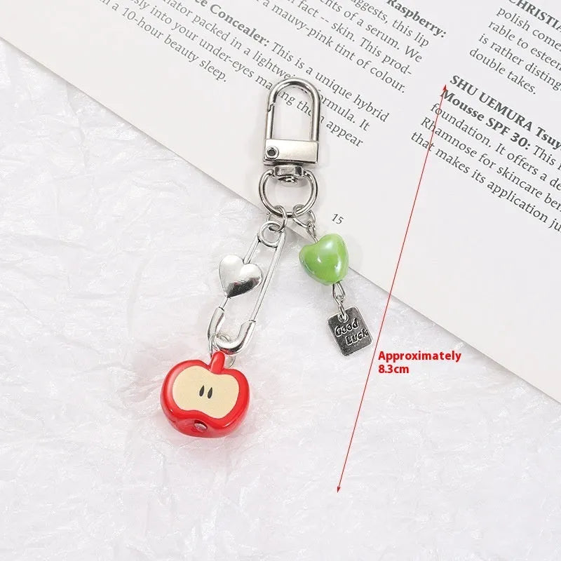 Red and green fruit-themed plastic mobile phone charm and keychain on a white background.