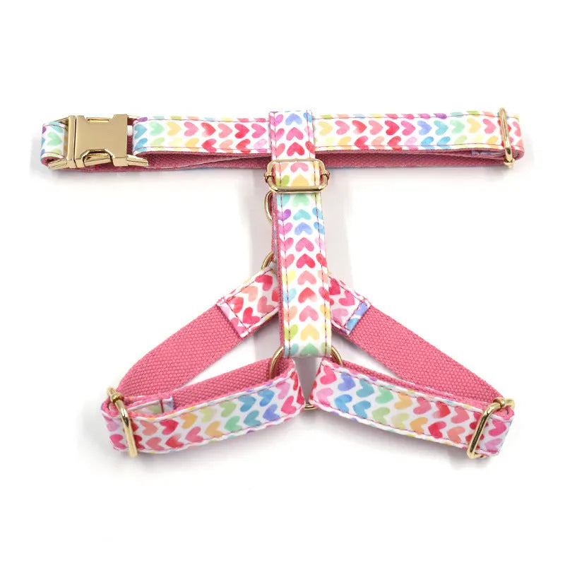 Pink colourful dog harness with heart-shaped stone details and a gold buckle on a white background.