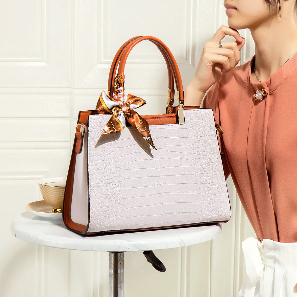 Women's milky white shoulder handbag with three interior compartments showing zipper changing bag, mobile phone pocket, and document storage