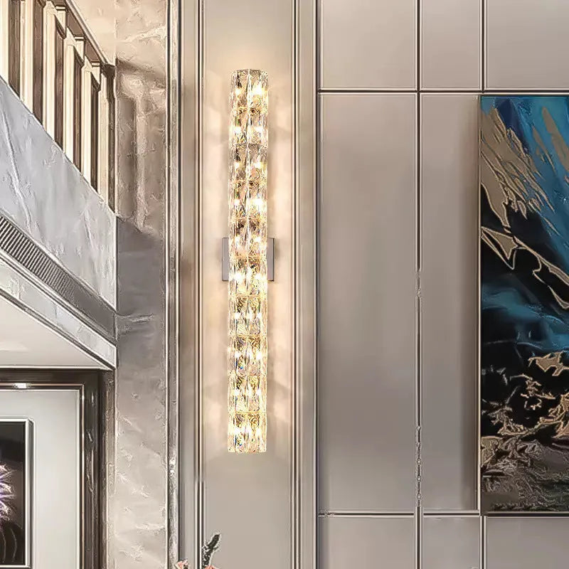 A sleek crystal wall lamp with a stainless steel base in chrome finish, mounted on a wall.