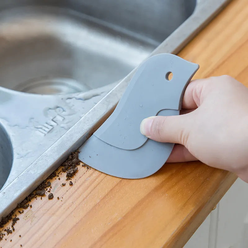 Green penguin-shaped kitchen scraper with soft blade, 11cm by 7cm, for cleaning plates and pots