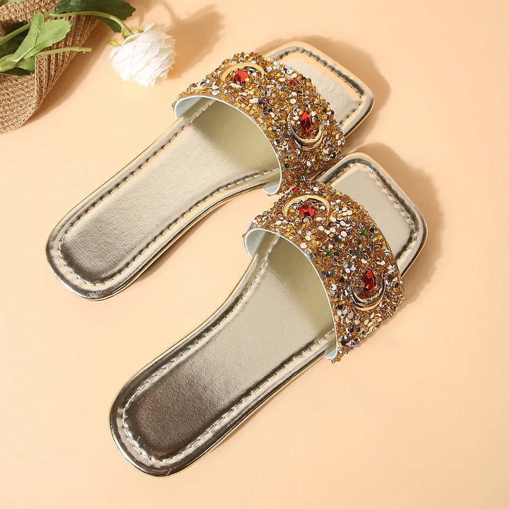 Gold women's flat slippers decorated with rhinestones and sequins on a PU upper with a rubber sole.