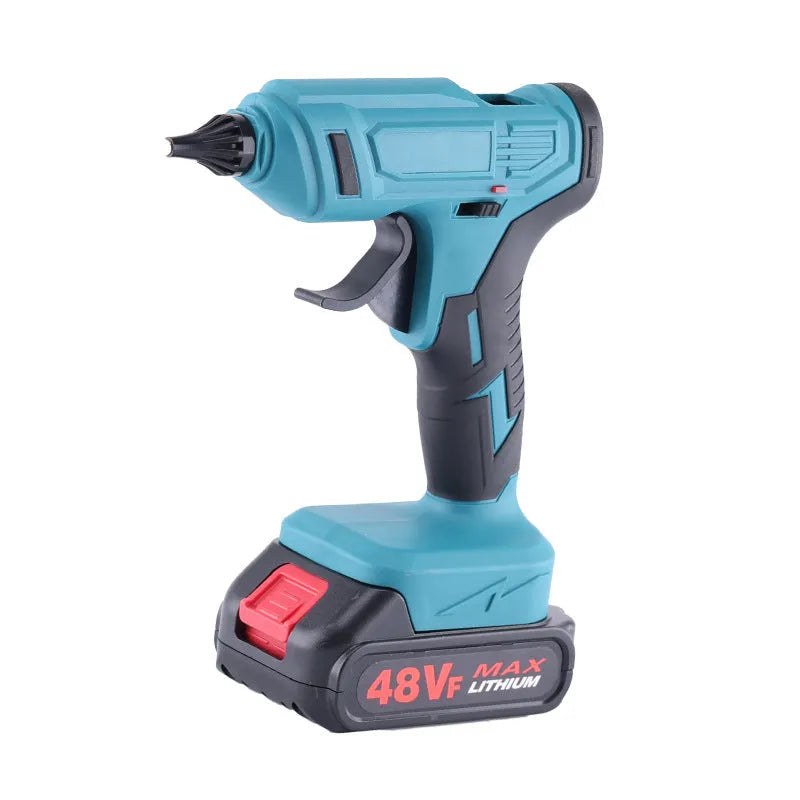 Cordless hot glue gun with two batteries, a charger, and a pack of glue sticks on a workbench.