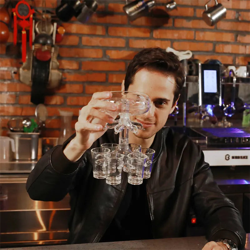 Transparent 6-shot glass dispenser rack with six shot glasses on a bar table.