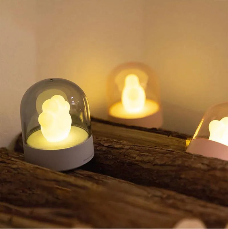 Grey cat paw shaped night light with USB charging port and control button showing soft illumination
