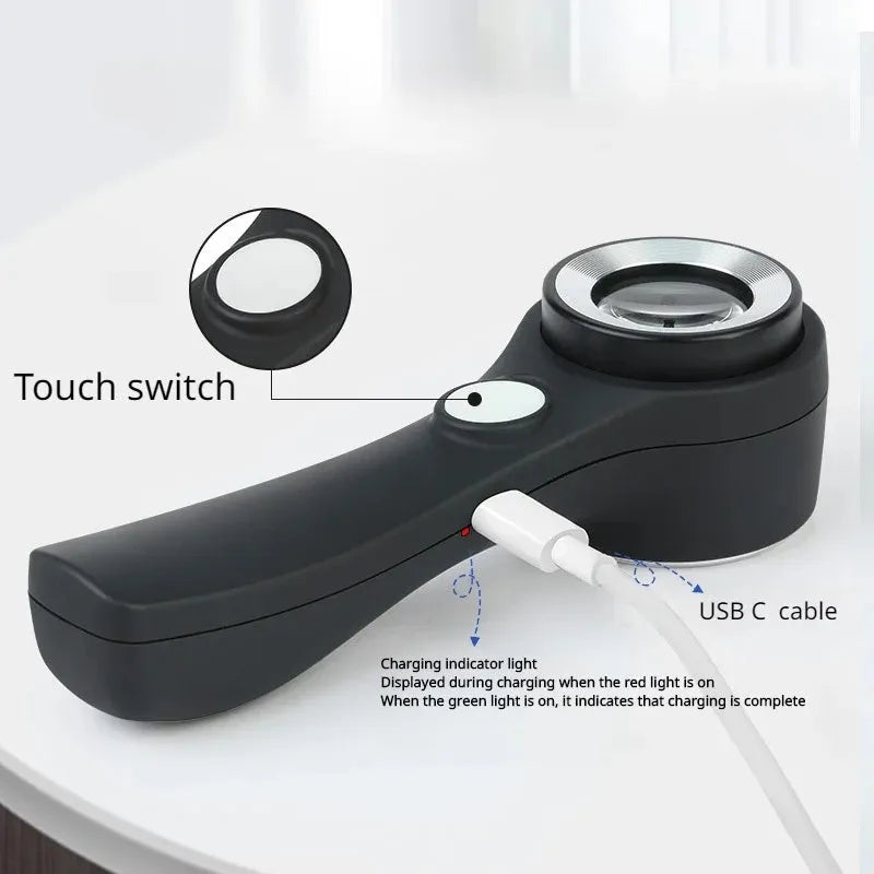 Black and silver jewellery appraisal magnifying glass with optical glass lens and USB-C cable on a table.
