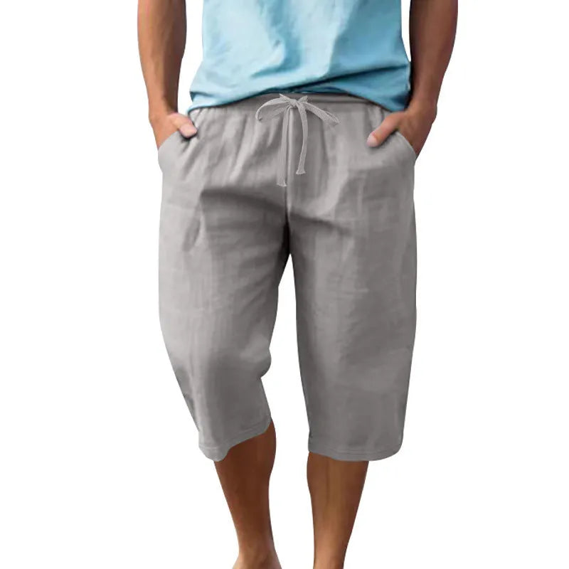 Men's solid colour linen shorts in a loose, cropped style on a drawstring waist.