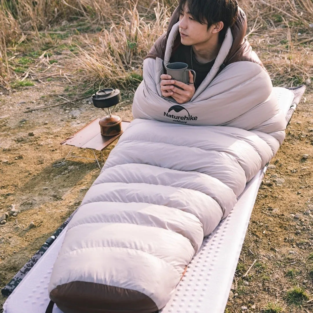 Mummy-style goose down sleeping bag in storage bag, showing colour options and weight specifications for outdoor use