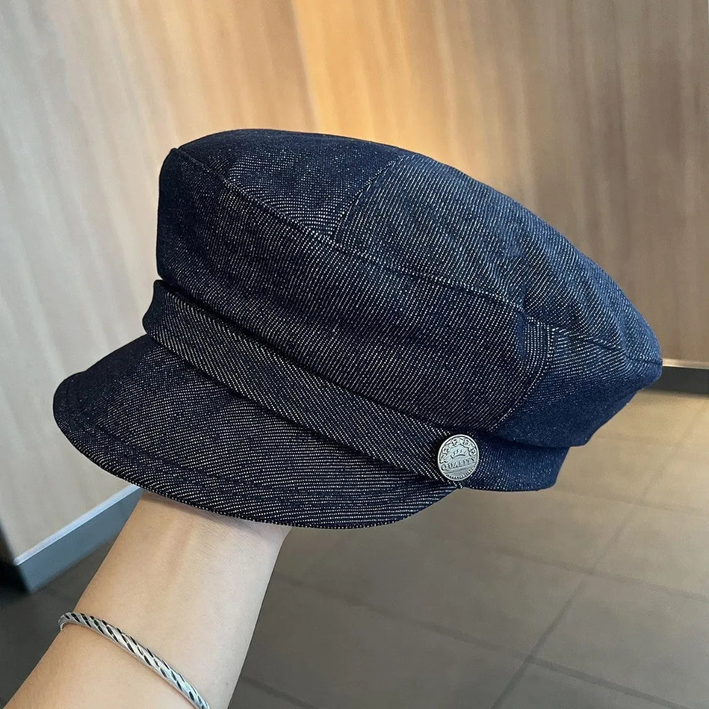 Dark blue denim British retro octagonal newsboy cap with an adjustable strap and coloured brim option on display.