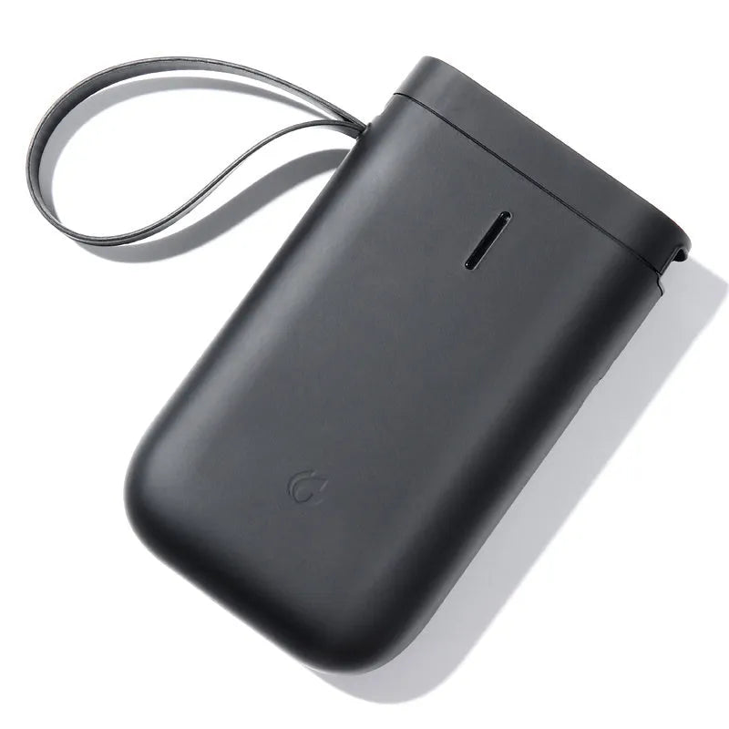 D11 compact Bluetooth thermal label printer in black on a desk next to a smartphone showing the control app.