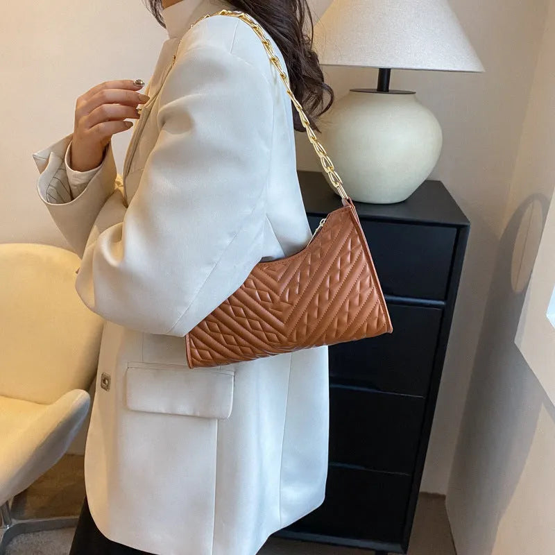Brown pleated chain baguette shoulder bag with adjustable strap and soft carry handle showing three-dimensional pocket design