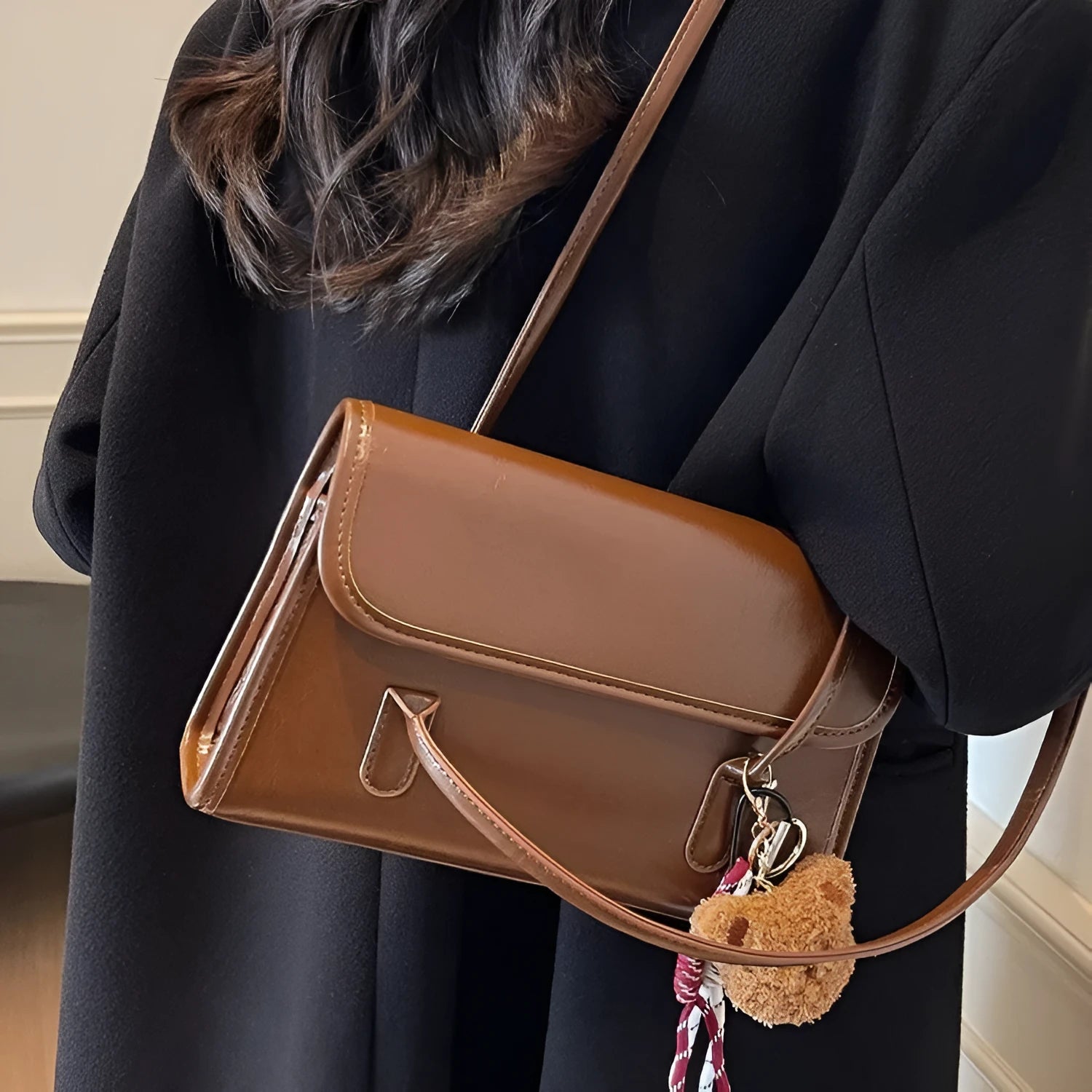 Brown women's structured shoulder bag with horizontal square shape, pendant accessory, and double joint shoulder straps