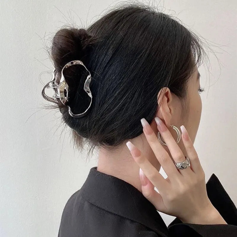 Assortment of silver metal hair claw barrettes in various shapes including waves, bows, and crosses.