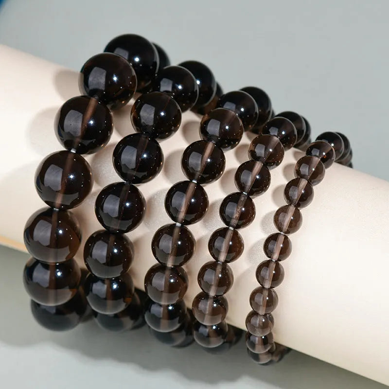 Hand-woven obsidian bracelet with round beads in adjustable sizes from 8mm to 16mm diameter, showing six colour options including black stone and rainbow eye obsidian.