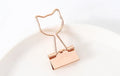 Golden alloy office clip with decorative top, 6.5cm long, holding papers on a desk