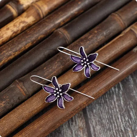 Purple flower-shaped alloy earrings with electroplated finish on white background