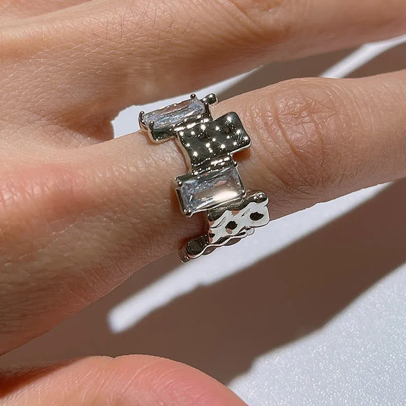 Silver geometric ring with open adjustable band and three-dimensional decoration, shown from multiple angles