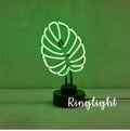 White bamboo-shaped desktop lamp with green light, USB cable, and minimalist design on wooden desk
