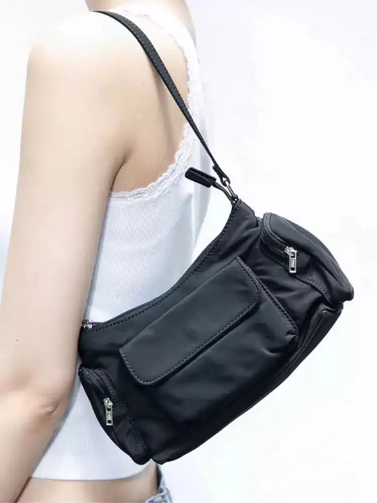 Black shoulder bag with two pockets showing side line detailing, measuring 24cm long by 9cm wide