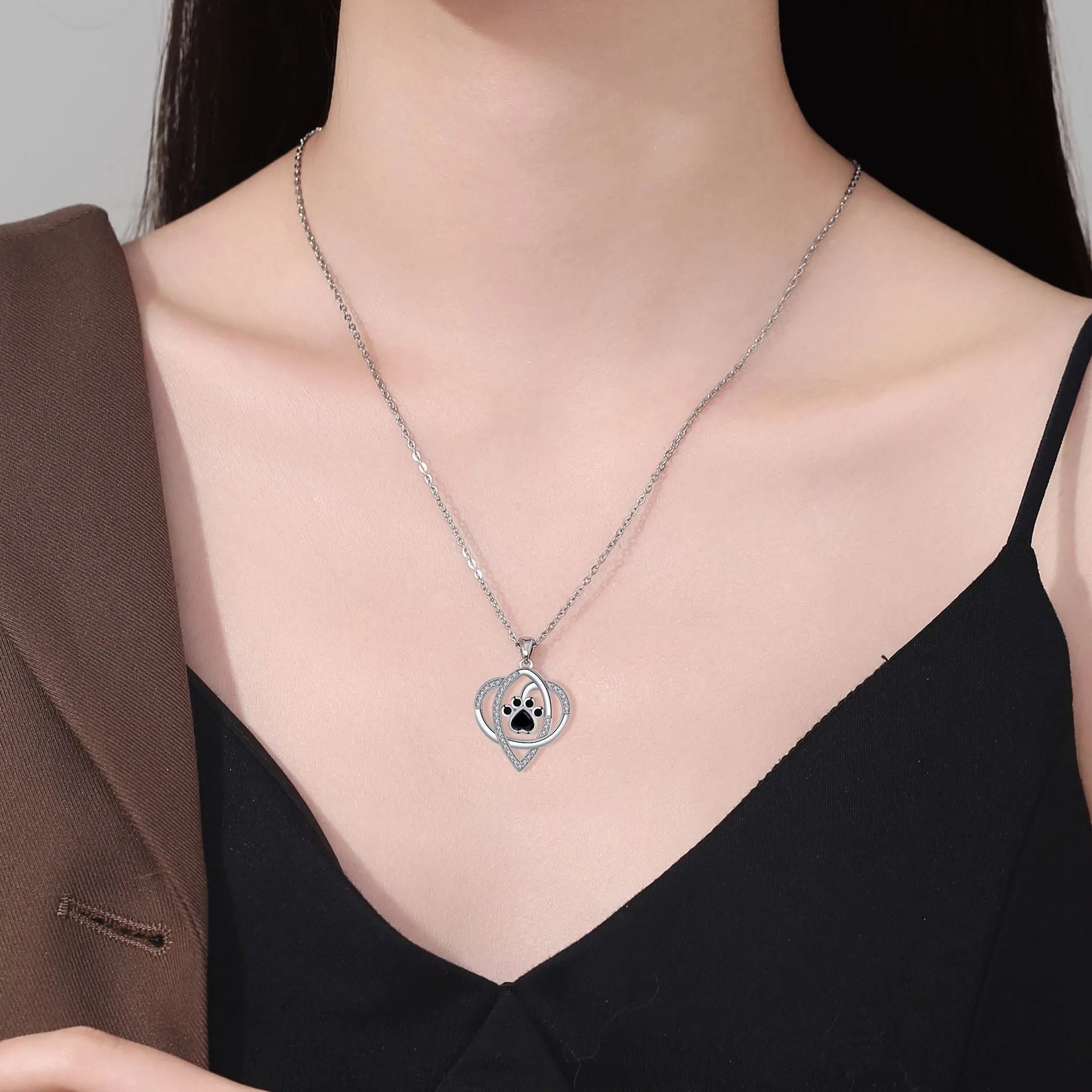 Copper pendant necklace showing cat and dog paw prints on a delicate cross chain.