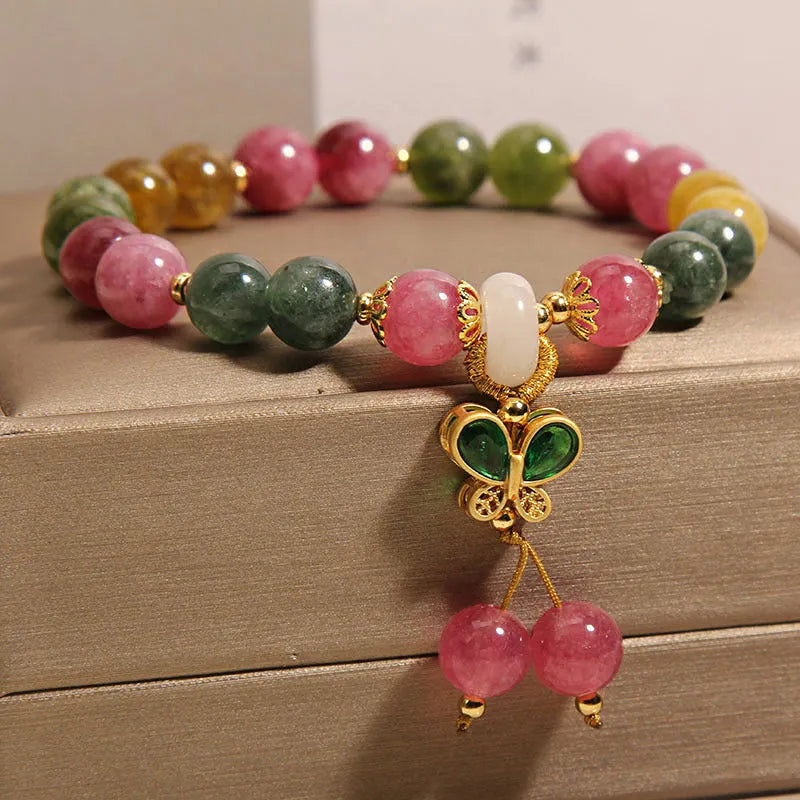 Colourful tourmaline butterfly pendant bracelet with rhinestone details on a woman's wrist.