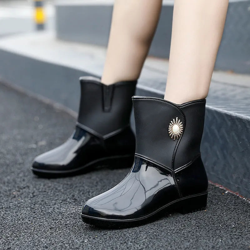 Women's purple PVC rain boots with a middle tube height and non-slip sole on a wet surface.