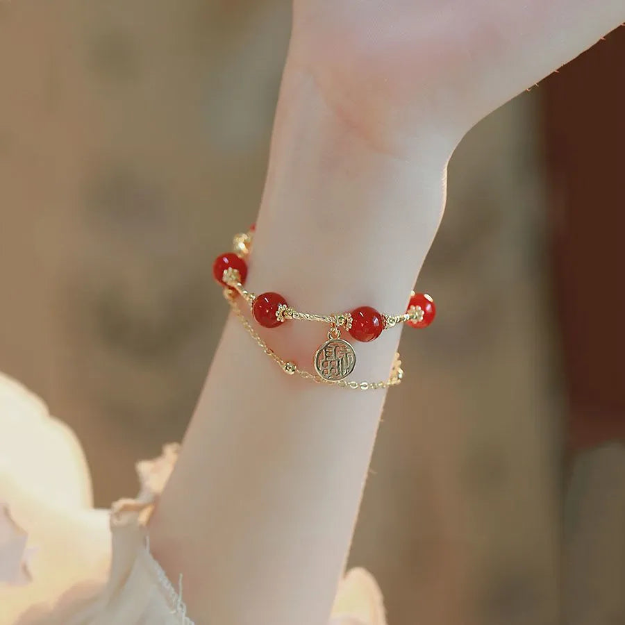 Close-up of a double-layer women's bracelet with a red agate blessing card and a red horse charm on an alloy band.