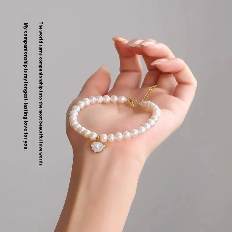 Freshwater pearl bracelet with fan-shaped shell design showing elastic and chain fastening options