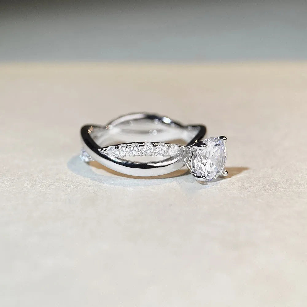 Geometric silver moissanite ring with twisted arm design and four-claw setting, shown in white diamond colour.