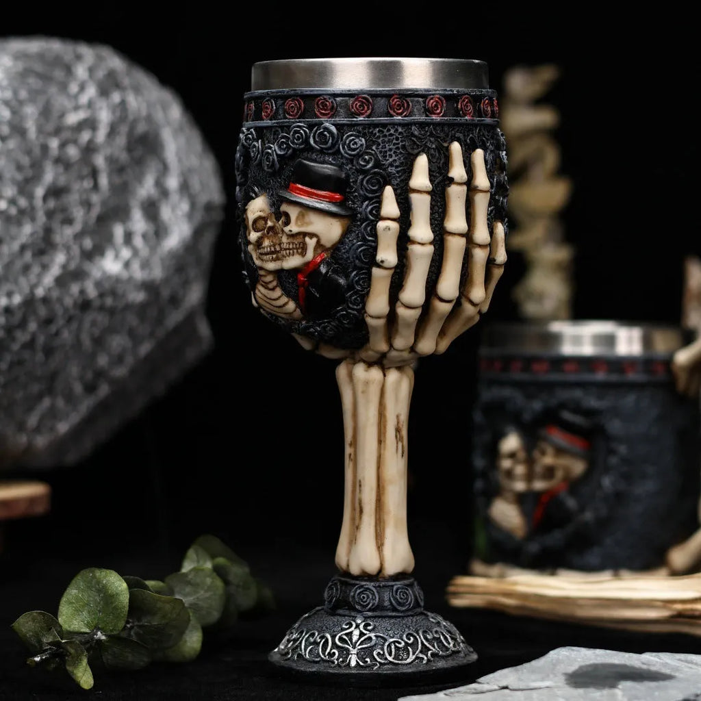 Two stainless steel red wine glasses with a detailed skeleton design, shown as a couple's set.