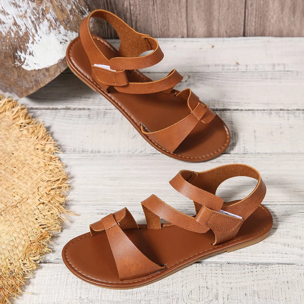 Women's black flat sandals with a round toe and a velcro strap fastening.