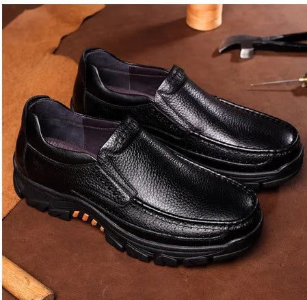 Black and brown leather business casual slip-on shoes with rubber outsoles on wooden floor