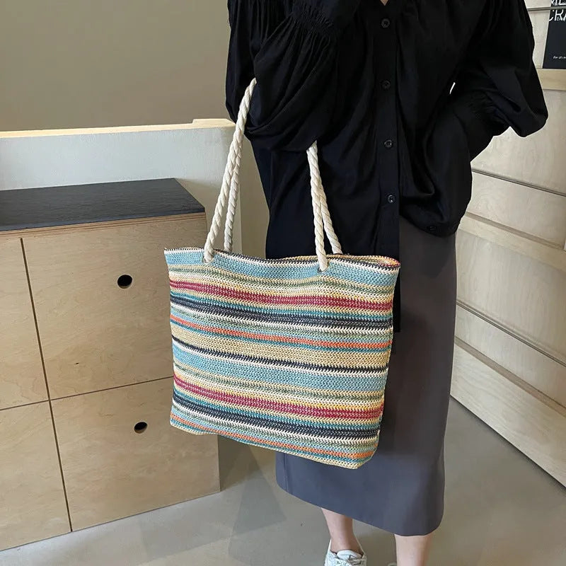 Blue straw woven large capacity shoulder bag with adjustable strap on a neutral background