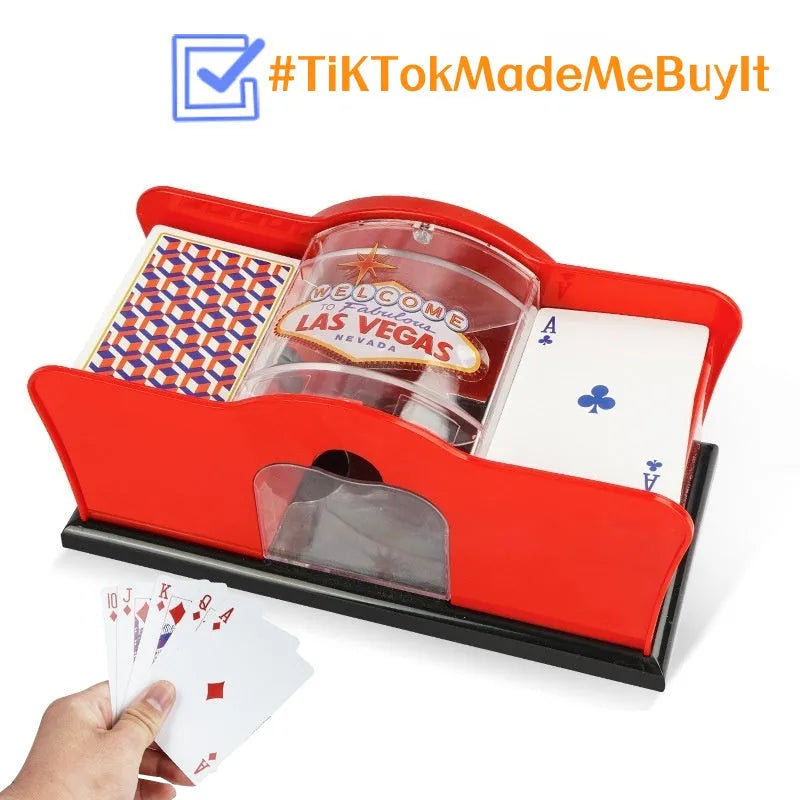 Black manual card shuffler with hand crank on a table next to playing cards.