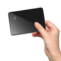 Black credit card sized pet tracker with a hanging hole, showing wireless charging and NFC symbols.